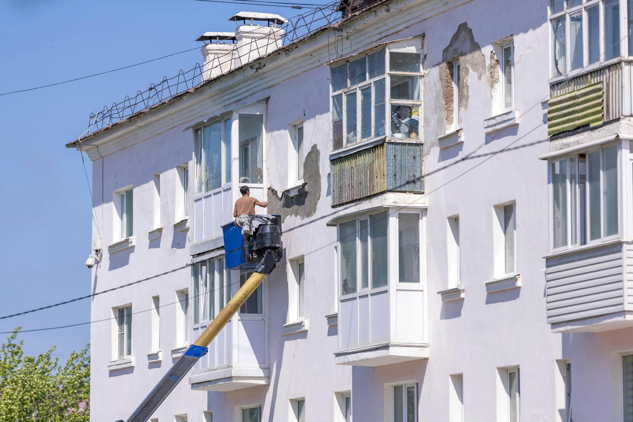 Profissional de manutenção predial inspecionando fachada, instalações ou área técnica de edifício.