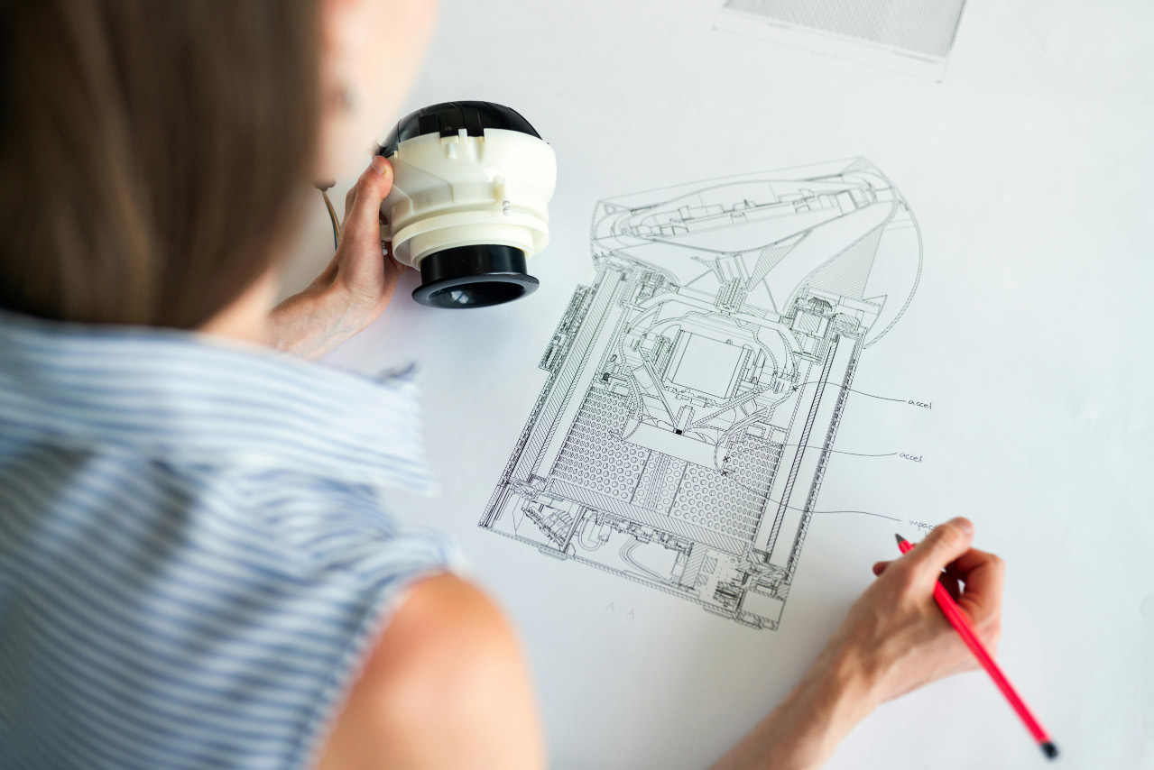Engenheiros analisando planta ou projeto técnico de construção sobre uma mesa de trabalho.